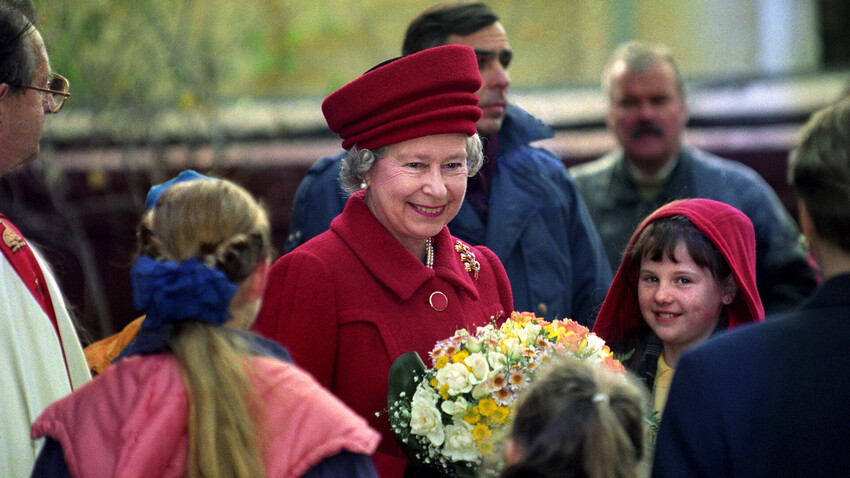 La regina Elisabetta II sorride mentre porta dei fiori all'uscita della chiesa di Sant'Andrea a Mosca