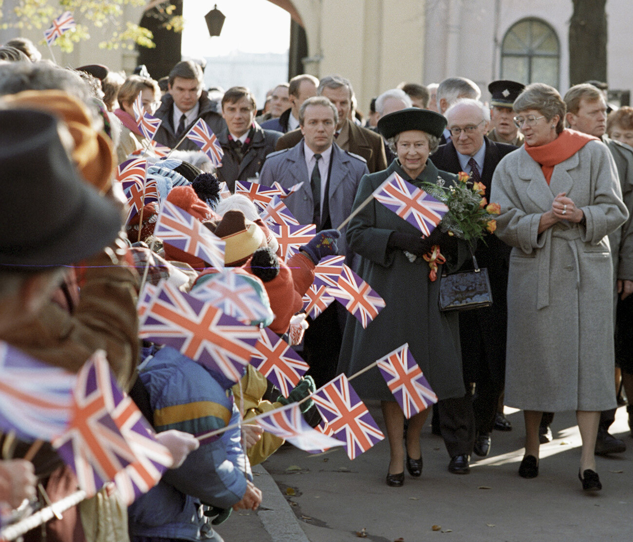 Kraljica Združenega kraljestva in Severne Irske Elizabeta II. (v sredini) se med obiskom trdnjave Petra in Pavla sprehodi mimo ljudi, ki jo pozdravljajo z zastavami z britanskimi simboli; uradni obisk Elizabete II. in princa Filipa v Rusiji