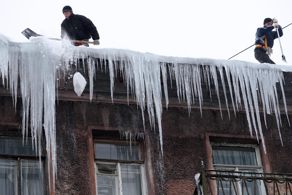 Municipal workers breaking dangerous icicles from the roof of a building in downtown in St Petersburg.