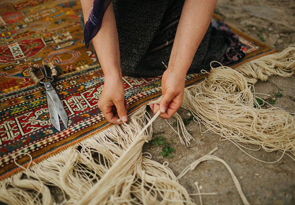 The women have finished their work. After one of them has cut the main threads, they ceremoniously take their beautiful rug into the courtyard.