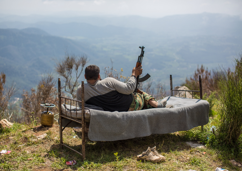 Sirski vojak leži na postelji na pregledni višini nad mestom Kessab, 2014.