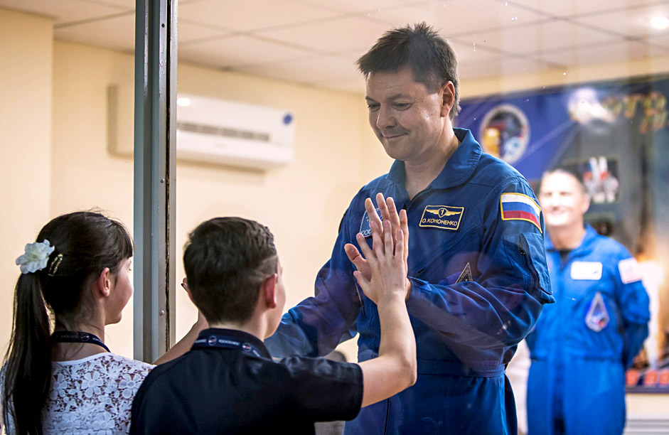 The ISS crew member Oleg Kononenko of Russia interacts with his children as he stands behind a glass wall at a news conference at the Baikonur cosmodrome in Baikonur, Kazakhstan, July 21, 2015. The crew is scheduled to travel on board the Soyuz spacecraft on July 23, 2015. 
