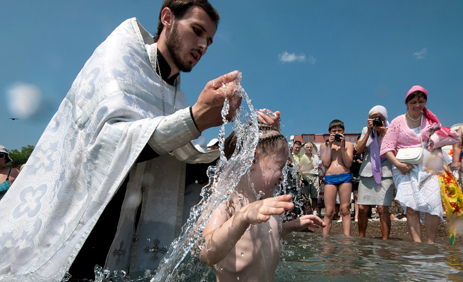Православен свещеник кръщава дете по време на празнуването на 1000-годишнината от смъртта на Владимир Велики, който е известен с покръстването на Киевска Рус.