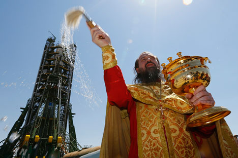 Orthodoxer Priester spricht einen Segen vor Sojus-Raumschiff TMA-13M aus, das vom Startplatz am Bajkonur-Kosmodrom absetzt. 