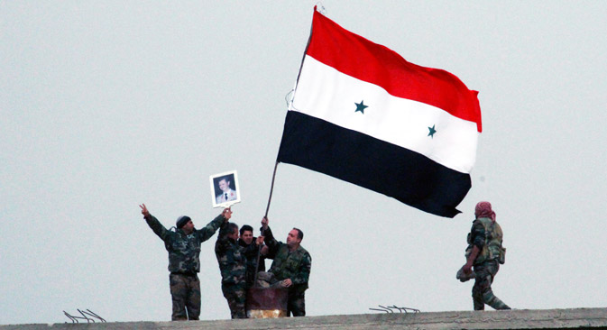Syrian soldiers hold the national flag and photo of Syria President Bashar Assad atop a building at Deir al-Adas town in the southern province of Daraa, Syria, 11 February 2015. According to the official SANA, the Syrian army gained control over the strategically area of Deir al-Adas in Daraa province on 11 February
