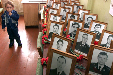 Un garçon debout à côté des portraits de victimes du naufrage du Koursk.