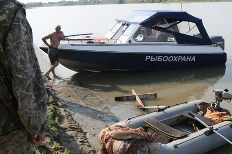 Policial conversa com caçador detido durante operação no rio Irtich