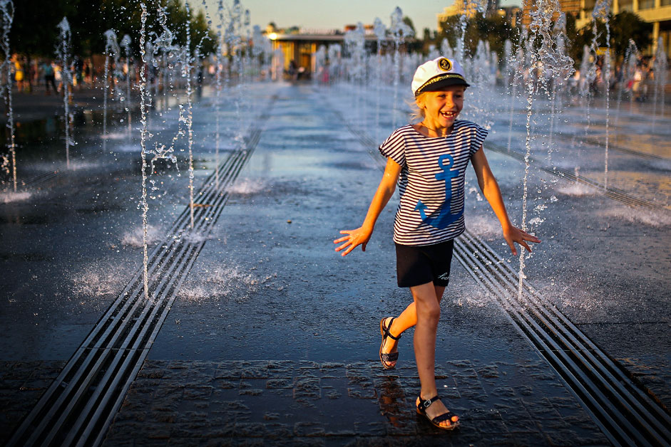 Una bambina attraversa le fontane nel parco Muzeon di Mosca per rinfrescarsi dal caldo degli ultimi giorni 
