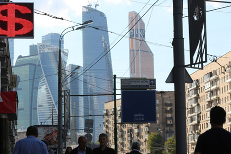 Sebuah gedung pencakar langit di daerah bisnis Moscow City, di belakang tempat penukaran uang, Moskow, Rusia (23/8). Rubel Rusia turun sebesar 2,3 pesen pada hari Senin dan menembus level terendah yang bertahan pada tujuh bulan terakhir mengikuti harga minyak, produk kunci ekspor Rusia.