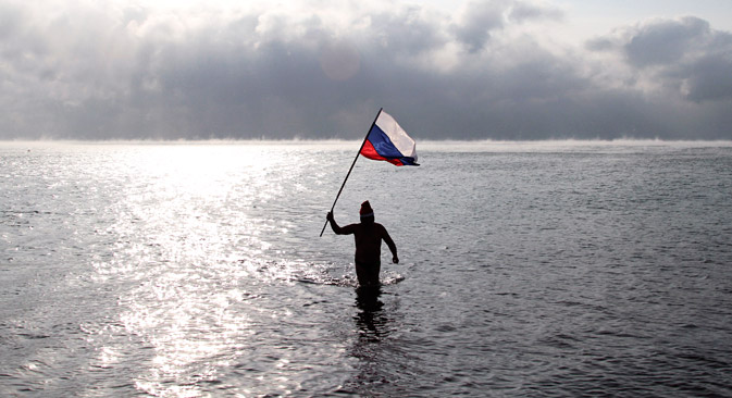 Un homme tenant le drapeau russe marche dans la mer Noire près de Evpatoria, en Crimée.