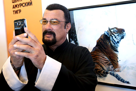 American actor Steven Seagal (C) takes a selfie an exhibition stand of the Amur Tiger Centre at the 2015 Eastern Economic Forum on Russky Island off Vladivostok, Russia on September 4, 2015