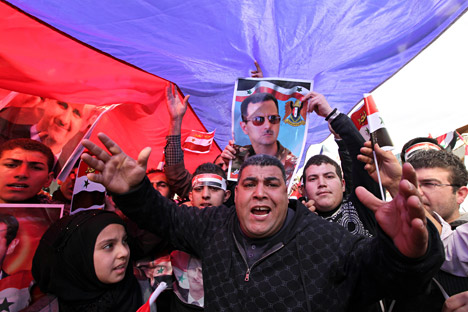 Pro-Syrian regime protesters chant slogans beneath a large Russian flag and a picture of President Bashar Assad during a demonstration, where anti-Syrian regime protesters and supporters of the Islamic group Jamaa Islamiya were also protesting, in front the Russian embassy, in Beirut, Lebanon, on Sunday, Feb. 5, 2012. Source: AP