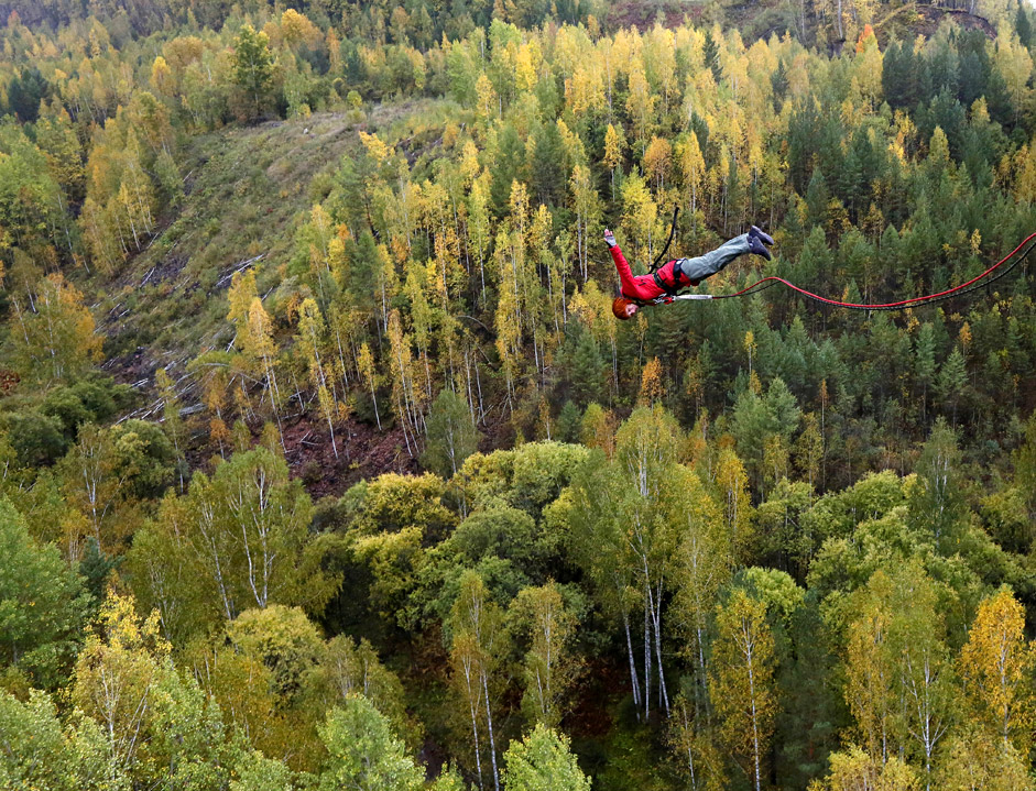 A member of the "Exit Point" amateur rope-jumping group jumps from a 44-metre high (144-ft) waterpipe bridge in the Siberian Taiga area outside Krasnoyarsk, September 13, 2015. Rope-jumping, an extreme sport, involves jumping from a high point using an advanced leverage system combining mountaineering and rope safety equipment. 