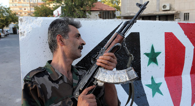 Seorang tentara bersenjata di sebuah pos pemeriksaan di pinggiran Damaskus, ibu kota Suriah.