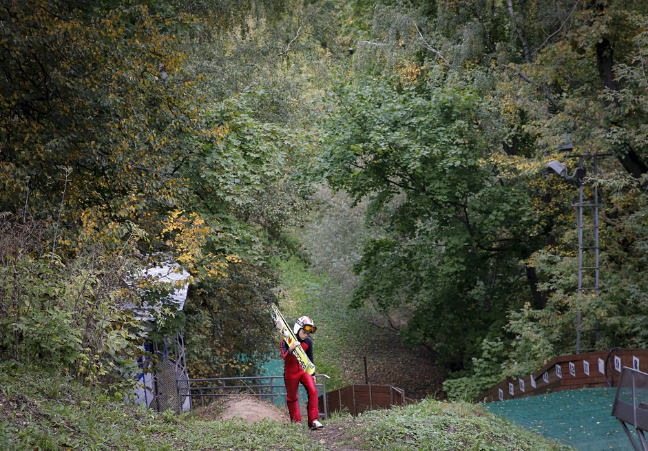 A young skier carries his skis through an autumn park near a ski jump complex in Moscow, Russia, September 20, 2015. 