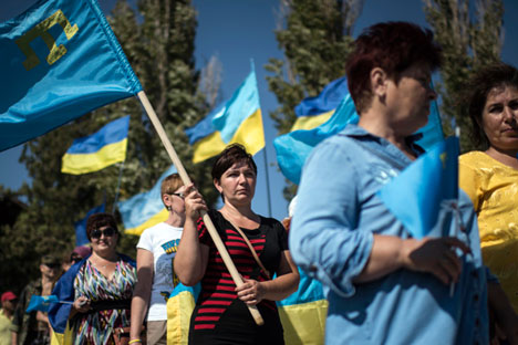 Local residents carry Ukrainian and Crimean Tatars flags in the village of Chongar, Ukraine, on Sunday, Sept. 20, 2015. The radical Right Sector group and Pro-Kiev Crimean tartars leadership organized improvised checkpoints on all three roads connecting the Ukrainian mainland and Russian-annexed Crimean peninsula, aiming to prevent trucks carrying goods to cross Russia-Ukraine border.