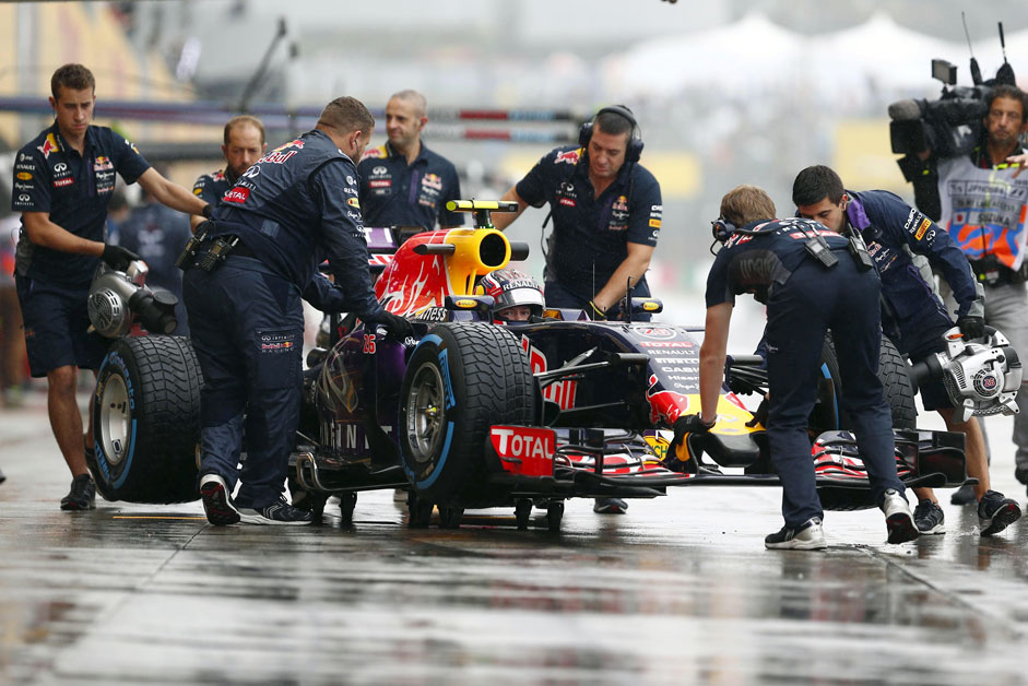 Crew members push Red Bull Formula One driver Daniil Kvyat of Russia back into the garage during the first practice session in Suzuka, Japan, September 25, 2015, ahead of Sunday's Japanese F1 Grand Prix.
