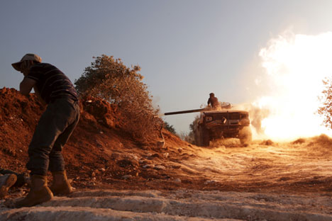 A rebel fighter of the Al-Furqan brigade covers his ears as a fellow fighter fires a vehicle's weapon during what the rebels said is an offensive to take control of the al-Mastouma army base which is controlled by forces loyal to Syria's President Bashar al-Assad near Idlib city May 17, 2015.
