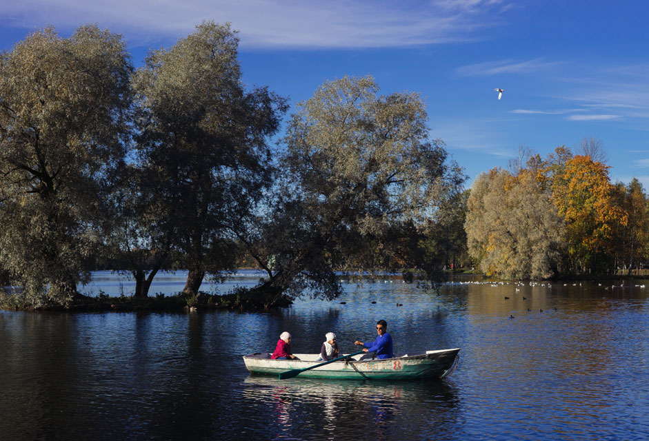 Besucher des Palastes der Stadt Gattschina fahren Boot im Park.