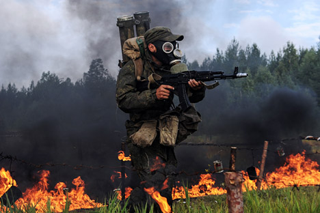 Salah seorang personil tentara NBK Rusia berlari melewati api dengan pakaian khusus NBK selama pelatihan militer tahunan di daerah Sverdlovsk, Rusia, 21 Augustus 2014.
