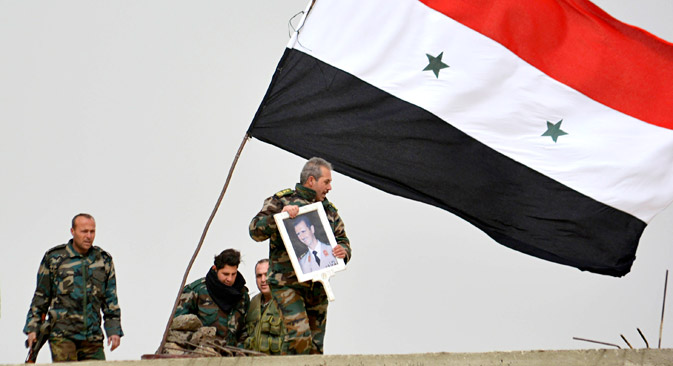 Pasukan Pemerintah Suriah yang loyal terhadap Presiden Suriah Bashar Al-Assad memegang foto Assad dan bendera Suriah setelah berhasil merebut kembali kota Deir al-Adas yang terletak di selatan Damaskus, pada Februari 2015 lalu.