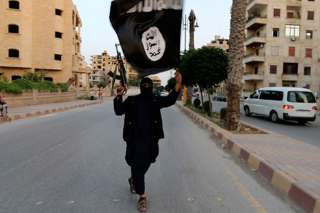 Seorang simpatisan ISIS melambaikan bendera organisasi teroris itu di Raqqa, Suriah, 29 Juni 2014.
