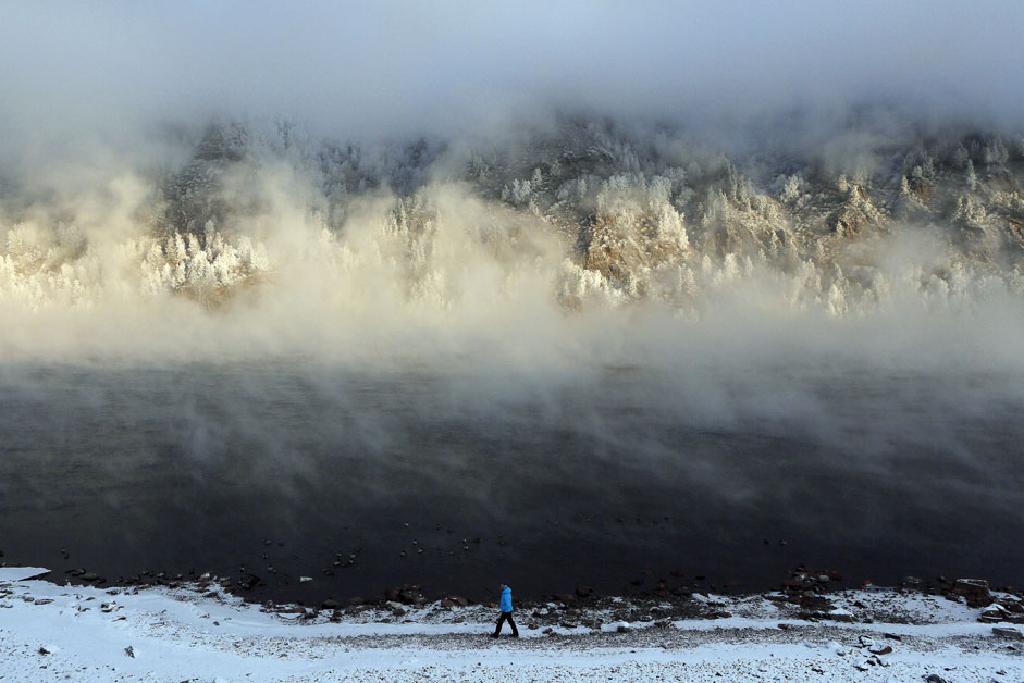 Жена върви по брега на Енисей, над който се издига ледена пара. Температурата на въздуха в гр. Дивногорск, близо до Красноярск, е -26°С.