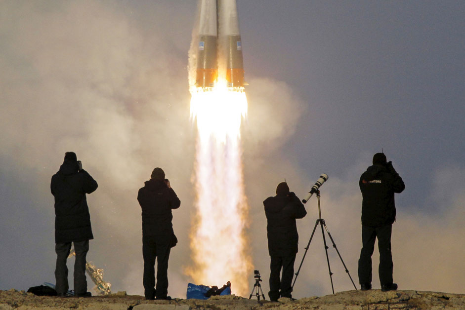 Photographers take pictures as the Soyuz TMA-19M spacecraft carrying the crew of Timothy Peake of Britain, Yuri Malenchenko of Russia and Timothy Kopra of the U.S. as it blasts off to the International Space Station (ISS) from the launchpad at the Baikonur cosmodrome, Kazakhstan