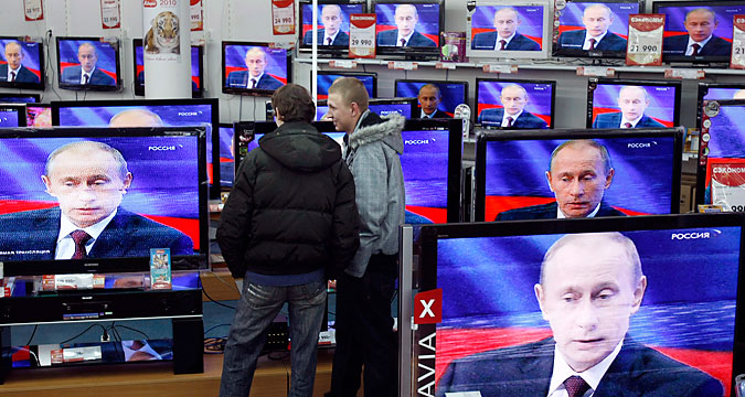 Men look at a television screening of Russia?s Prime Minister Vladimir Putin as he speaks during a question-and-answer show at a Russian state TV channel, at an electronics shop in Moscow December 3, 2009. Putin on Thursday said the Cold War-era Jackson-Vanik amendment that tied U.S. trade relations to emigration rights for religious minorities was an anachronism and hindered Russia's entry to the World Trade Organization (WTO). 