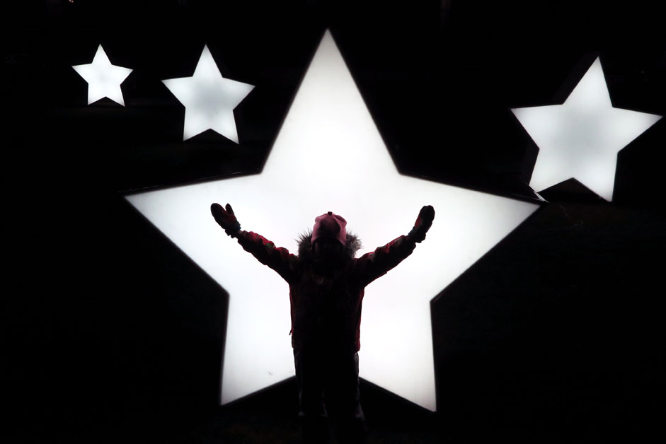 A child plays in front of illuminated stars set up in Gorky park in Moscow as preparation for the holiday season
