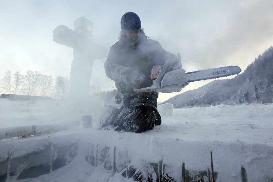 Hieromonch Nikandr from a local male skete operates a chainsaw while preparing an ice hole for the Orthodox Epiphany ceremony on the ice-covered Mana river, with the air temperature at about minus 30 degrees Celsius (minus 22 degrees Fahrenheit), in Taiga area near the Siberian village of Mansky outside Krasnoyarsk, Russia