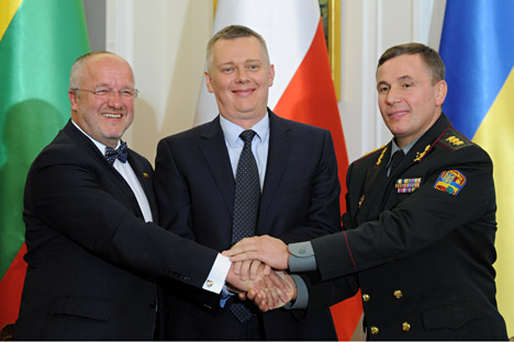 Defence ministers, of Lithuania Juozas Olekas, left, of Poland Tomasz Siemoniak, center, and of Ukraine Lt. Gen. Valeriy Heletei shake hands after signing an act forming a joint military unit, during a ceremony in Warsaw, Poland, Sept. 19, 2014. 