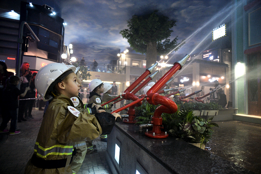 Children learning fire-extinguishing skills at the fireman area of the Kidzania game training park in Moscow.