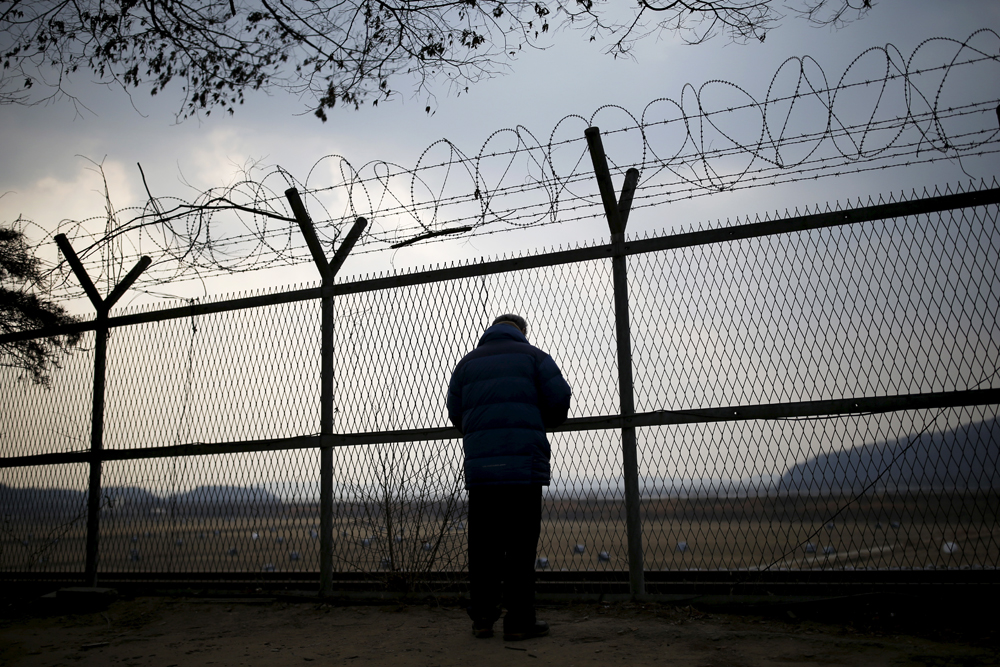 A man looks through a barbed wire fence near the demilitarized zone separating the two Koreas in Paju, South Korea, February 8, 2015.