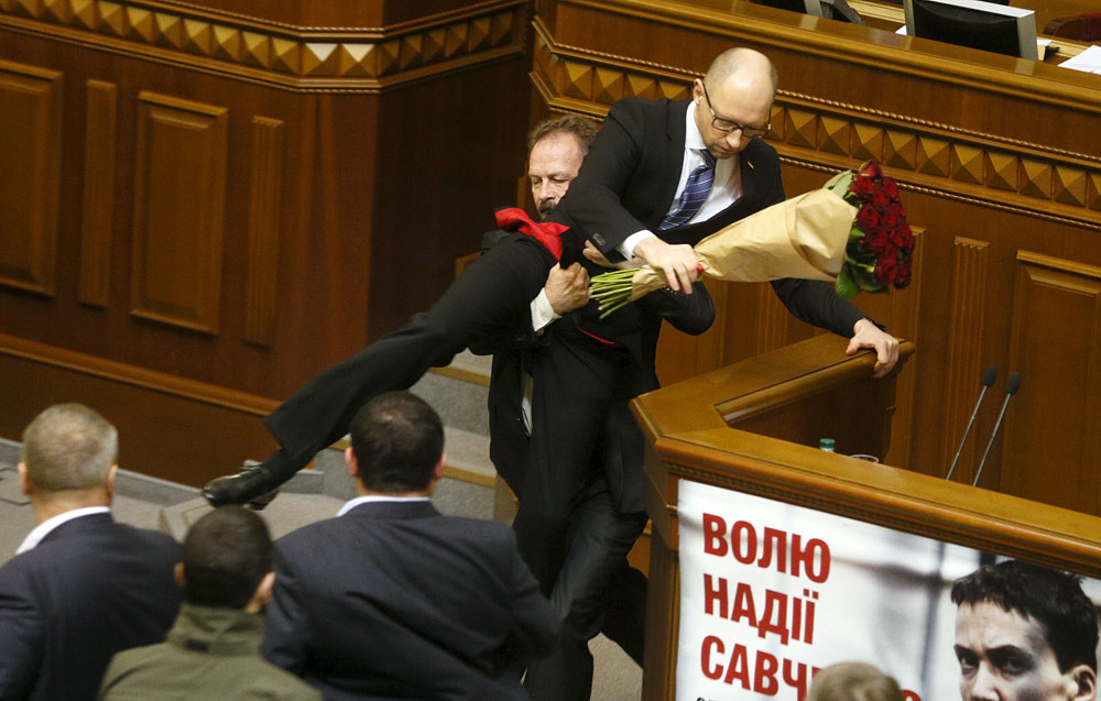 Rada deputy Oleg Barna removes Prime Minister Arseny Yatseniuk from the tribune, after presenting him a bouquet of roses, during the parliament session in Kiev, Ukraine