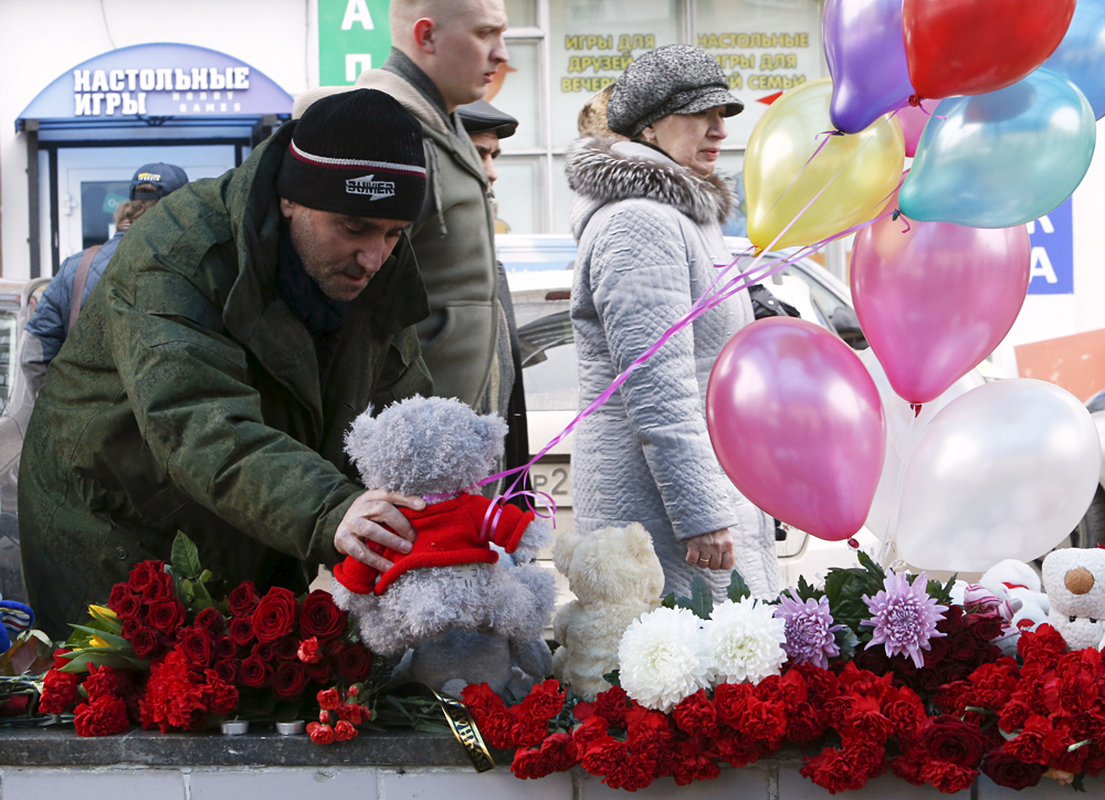 A man places a toy among flowers as people come to commemorate recently murdered child near the Oktyabrskoye Pole metro station in Moscow, March 1, 2016. 