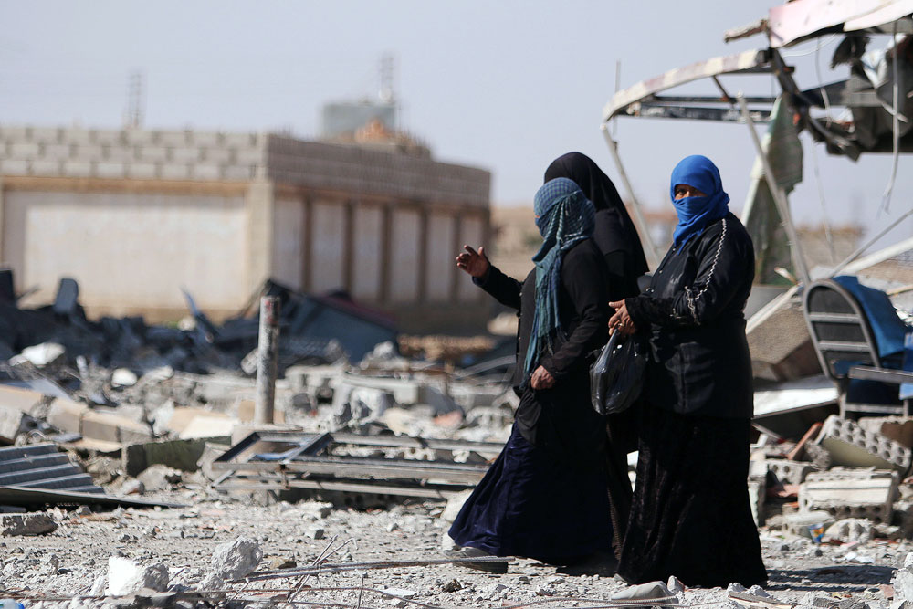 Beberapa orang perempuan Suriah berjalan di tengah reruntuhan di kota al-Shadadi, Provinsi Hasakah, Suriah.