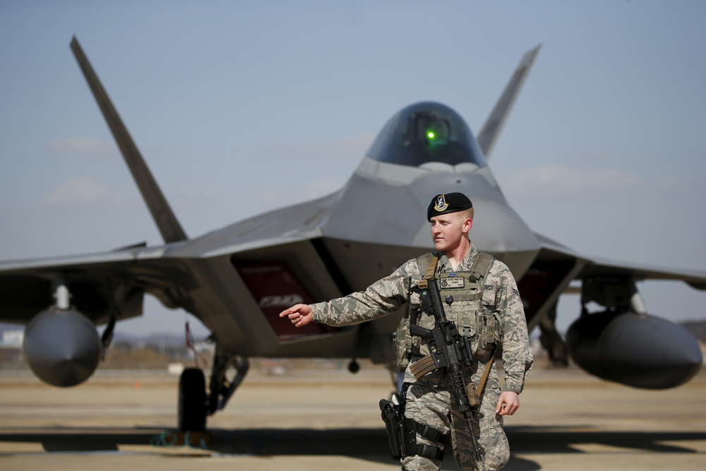 Seorang tentara AS berjaga di depan jet tempur siluman F-22.