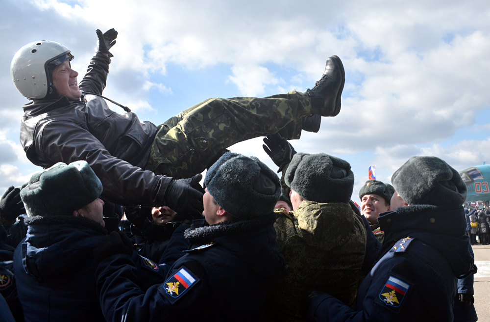 VORONEZH REGION, RUSSIA. MARCH 15, 2016. Russian military officers lift up a pilot of a Russian Air Force Sukhoi Su-34 fighter bomber, one of the first group of Russian military aircraft to return from Syria following an operation against the ISIL and other terrorist groups, during the arrival ceremony at a military installation in Voronezh Region. The Russian president has announced the withdrawal of the main part of Russia's military contingent from Syria, starting on March 15, 2016. 