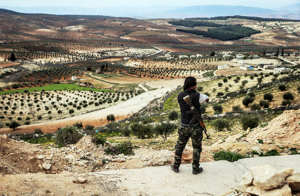 An armed Kurdish fighter surveys the area from an elevation near the town of Azaz on the Syrian-Turkish border.