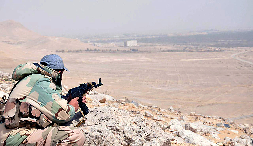 A member of the Syrian army taking position during an advance further in the vicinity of the ancient city of Palmyra, in central Homs province, March 24, 2016.