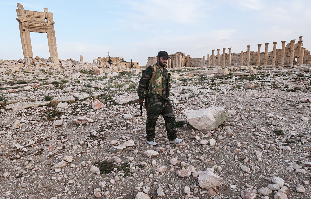 Seorang tentara pemerintah Suriah berdiri di antara puing-puing kuil Bel yang dihancurkan oleh militan ISIS di Palmyra.