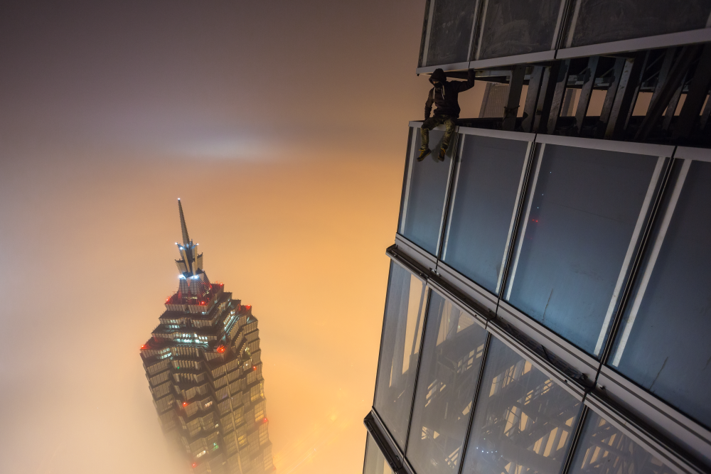 Тандемът получи международна слава след приключение в Шанхай през 2014 г., когато двамата смелчаги покориха шанхайски небостъргач (на снимката). На височина 650 м трябвало да чакат 18 часа, преди вятърът най-накрая да разсее облаците и да се открие гледка към града.