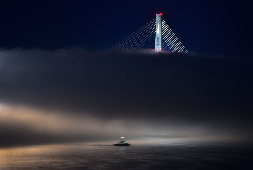 Нощна мъгла покрива моста Руски във Владивосток.