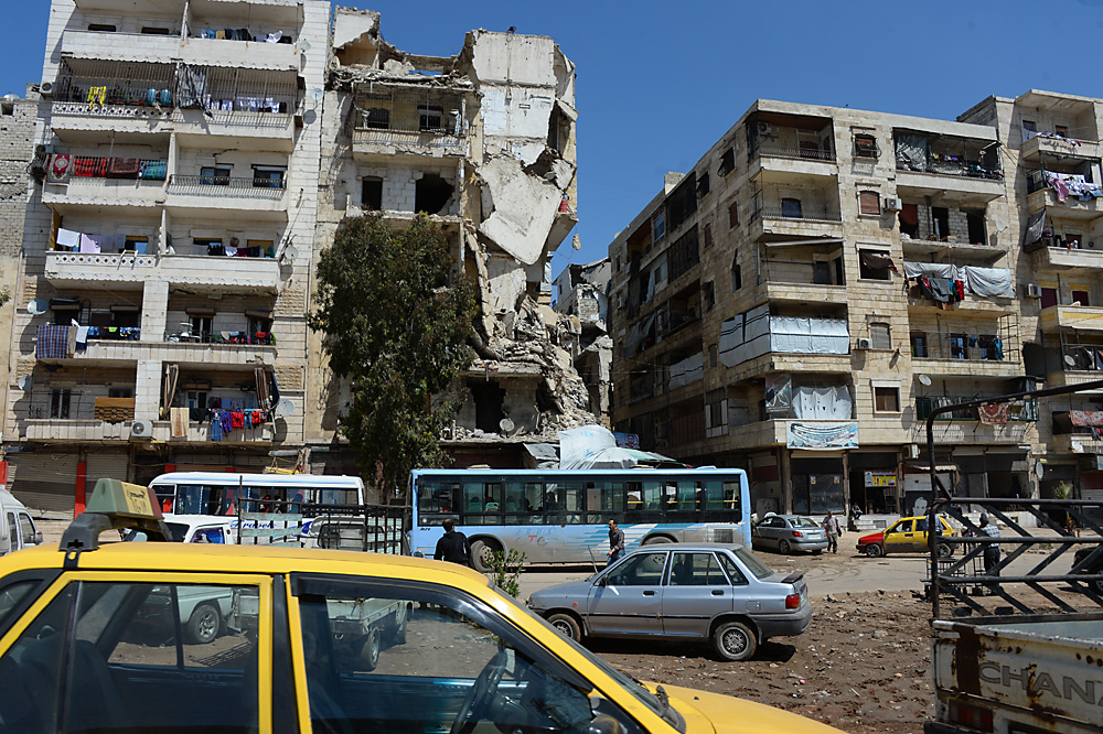 Sírios permanecem em edifícios destruídos do bairro de Salah ad-Din, em Aleppo, um dos mais afetados pela guerra 