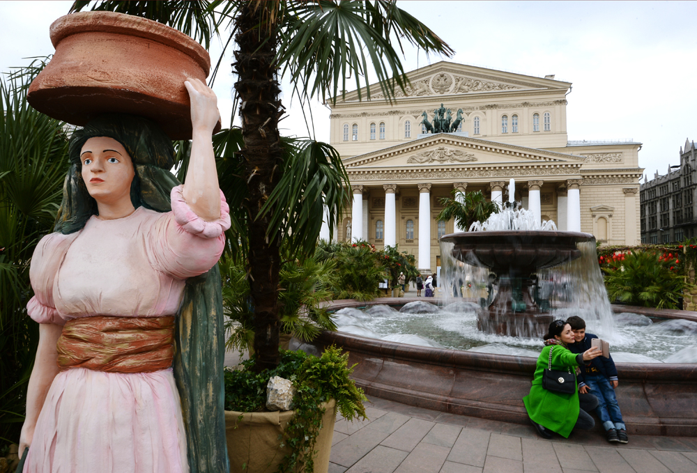 Горожане фотографируются у фонтана на Театральной площади в Москве.