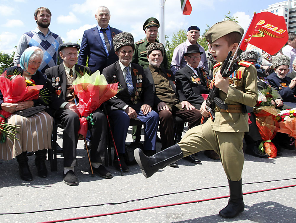 Чеченско момче, облечено в съветска  военна униформа от времето на Втората световна война, марширува с флаг по време на празнуването на Деня на Победата в Грозни, столицата на Чечня.