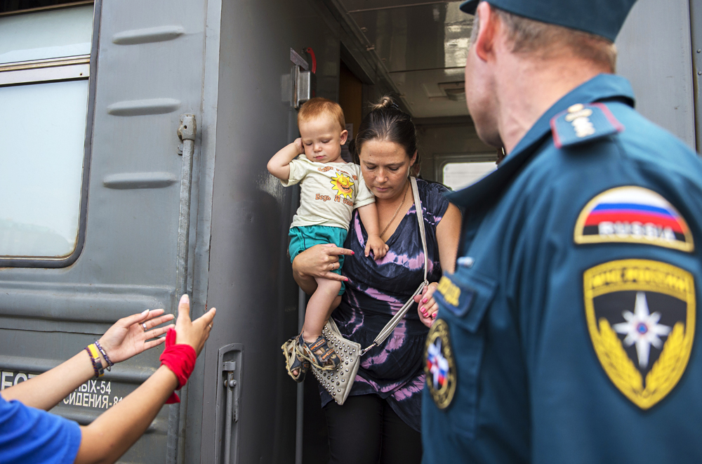 Работници и волонтери на Министерството за вонредни состојби на Русија пречекуваат украински бегалци на железничката станица во Омск.