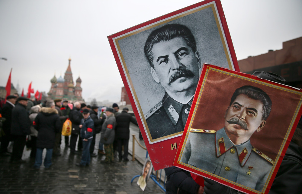 A man holds portraits of Josef Stalin before laying flowers at the grave of the Soviet leader during a ceremony to mark the 61th anniversary of Stalin's death in the Red Square in Moscow, March 2014. 