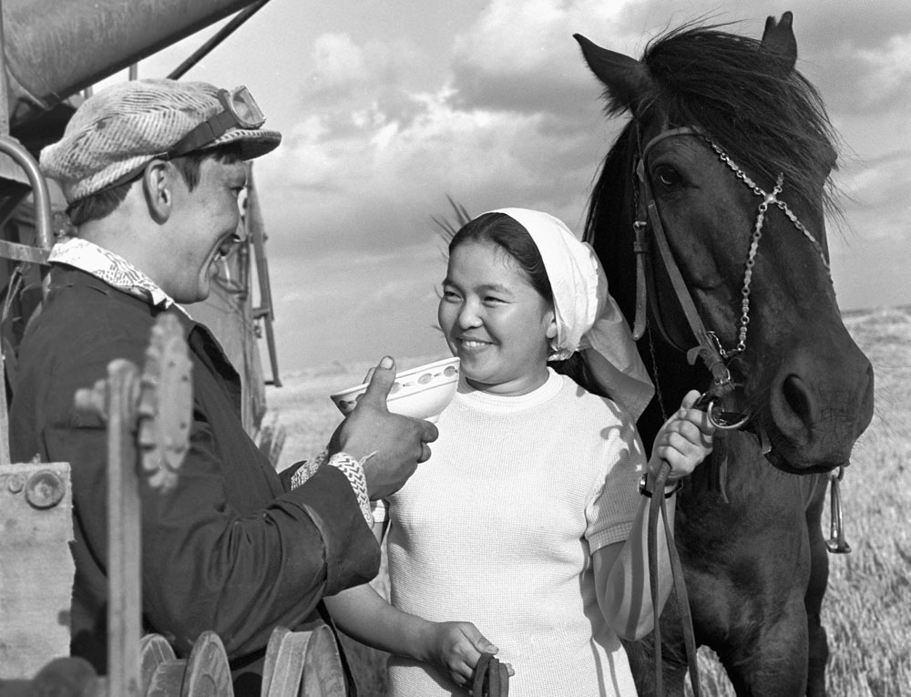 1976. Seorang pemerah susu dari Kazakhstan menawarkan semangkuk kumis (susu kuda) kepada seorang petani pembajak sawah.